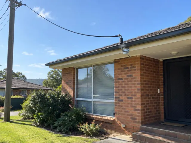 Overhead service cable and point-of-attachment bracket on a brick house fascia in Rankin Park
